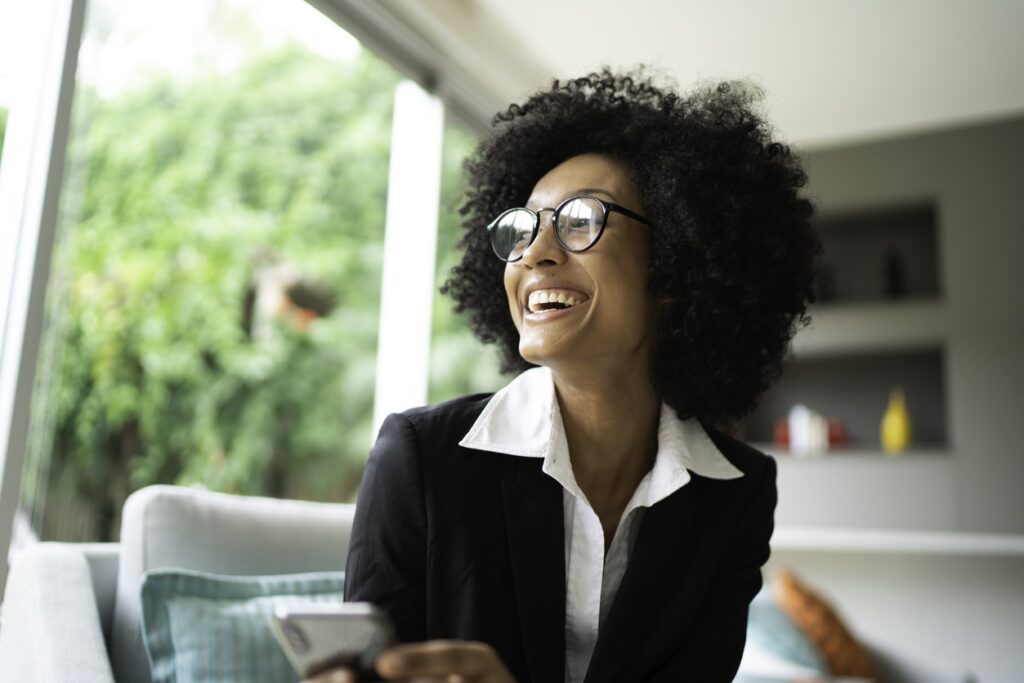 A woman in glasses and black jacket holding a phone.